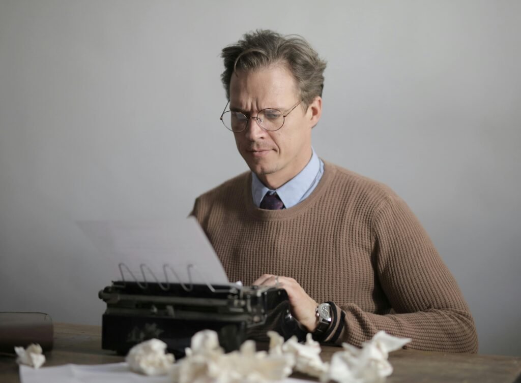 An author at a typewriter, using a free word counter tool to track the progress of his novel and meet daily writing goals.